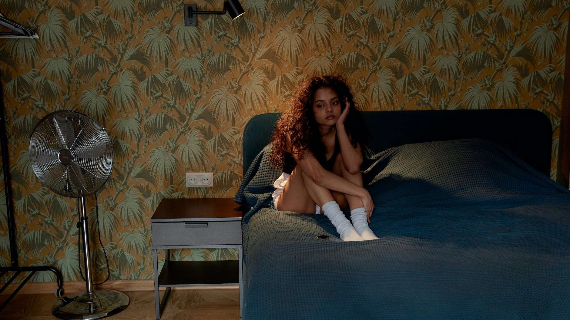 photo of a woman with curly hair sitting on the bed